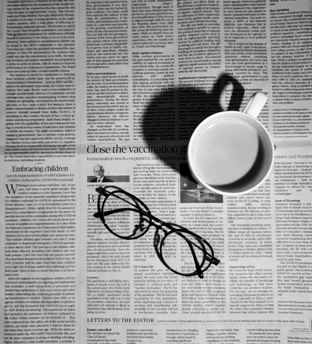 Periódico abierto junto a unas gafas y una taza de café